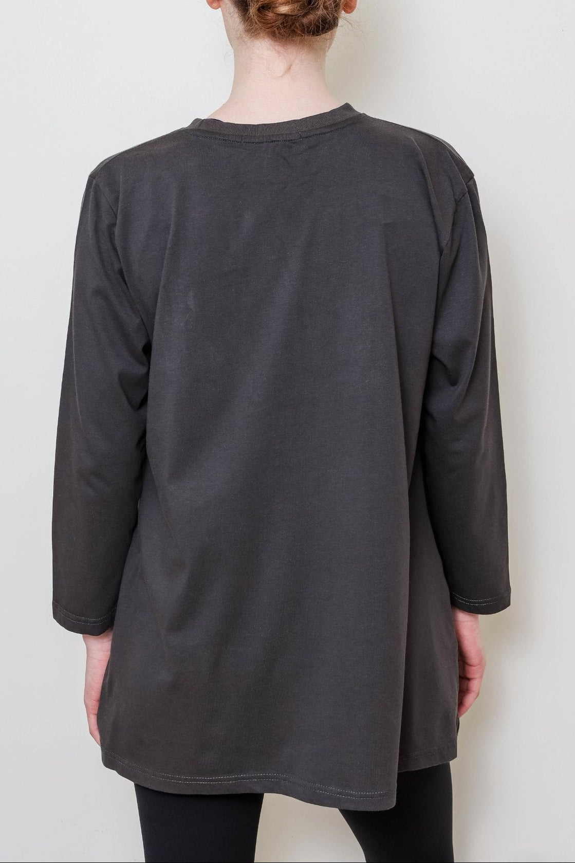 Person wearing a dark gray long-sleeve shirt against a plain background