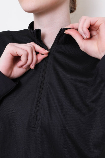 Person adjusting a black zip-up garment with a neutral background