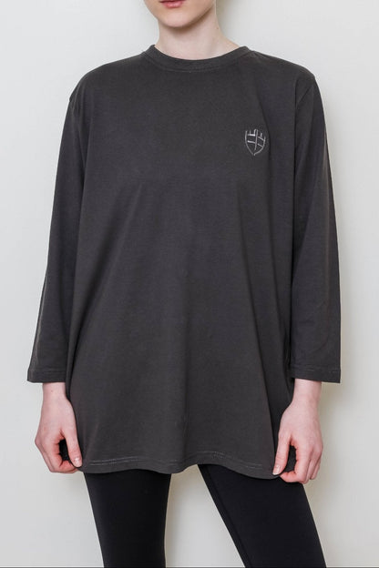 Woman wearing a gray long-sleeve shirt with a small logo on a white background